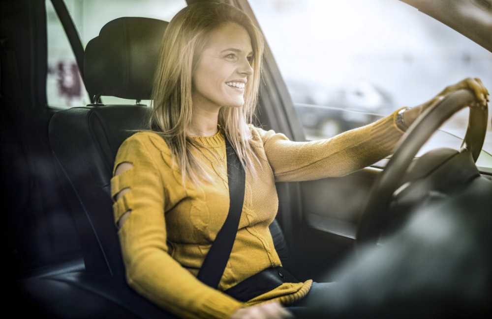 vrouw in auto achter het stuur met gele trui