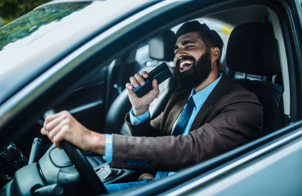 man lachend in auto zingend op telefoon