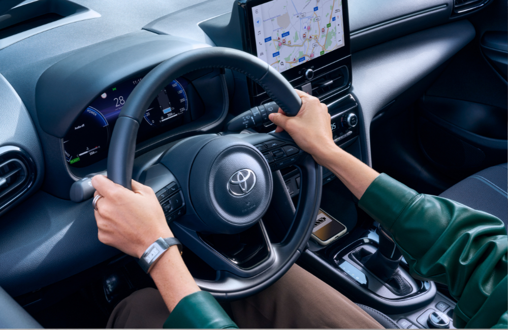 aan in stuur van toyota auto met apple carplay op de achtergrond en telefoon die draadloos oplaad