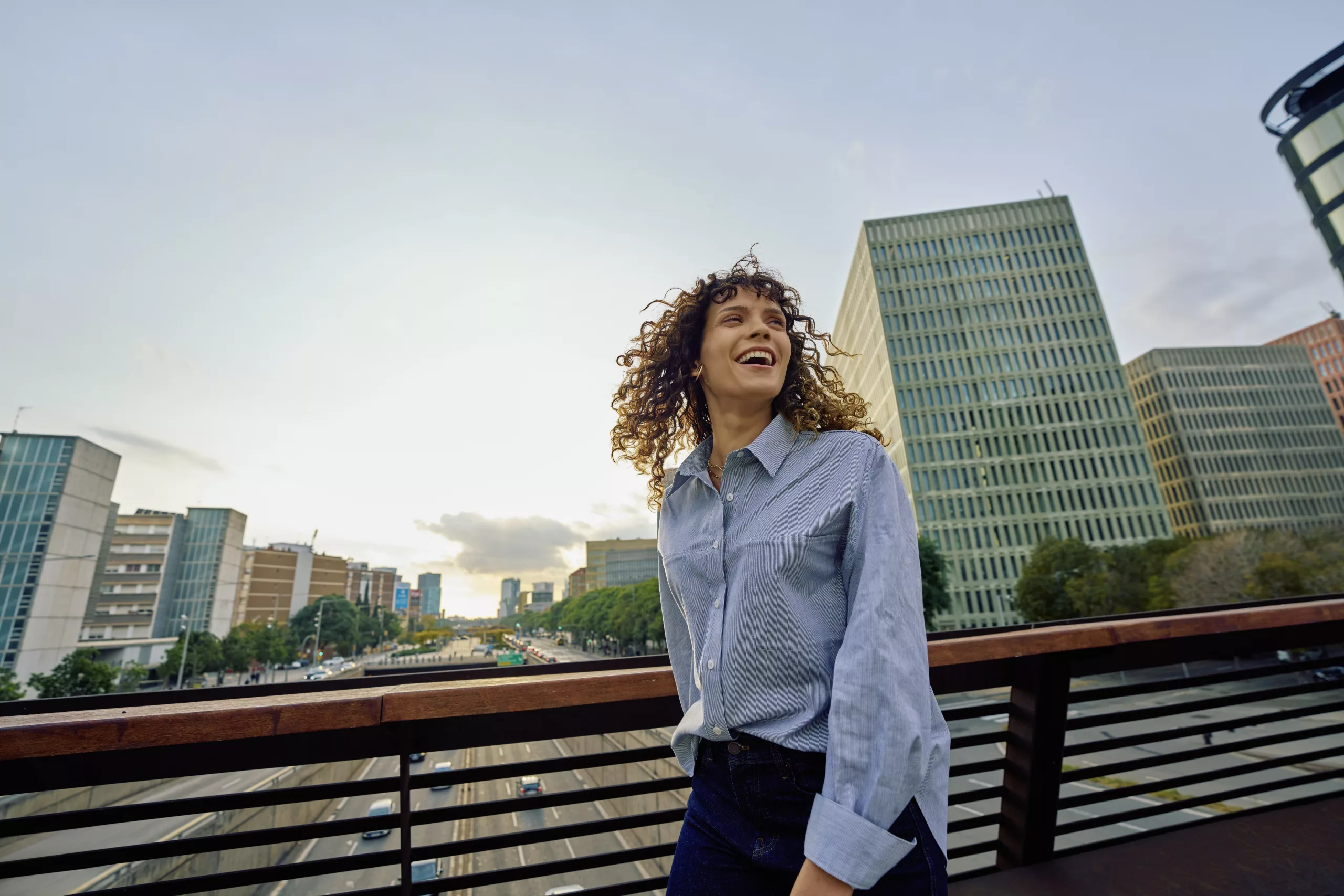 zakenvrouw lachend op brug over snelweg