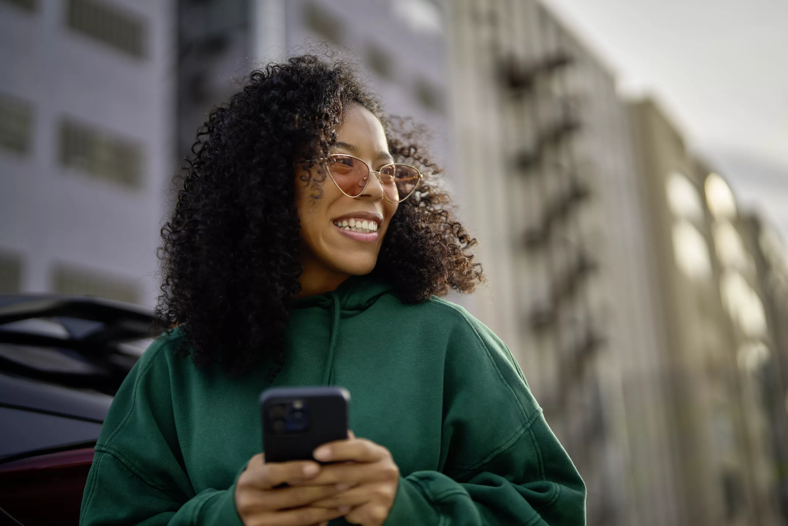 vrouw lachend op telefoon in groene trui